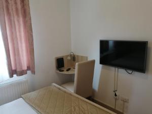 Zimmer mit einem an der Wand hängenden TV und einem Bett in der Unterkunft Wing Apartman Jagodina in Jagodina