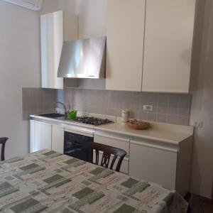 a kitchen with a stove and a counter top with a table at Appartamento fronte piscina in Montemarciano +4 photos