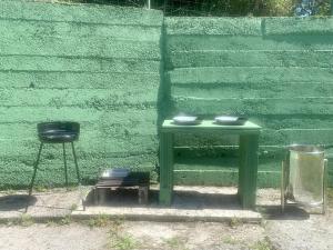 a green table and a stool next to a green wall at La Finca de Los Pisones in Lloreda