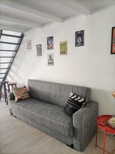 um sofá cinzento numa sala de estar com fotografias na parede em Maison 61 em Catânia