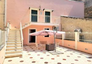 a pink house with a table and an umbrella at Uno Spettacolo Della Natura, Modern Style in San Lucido