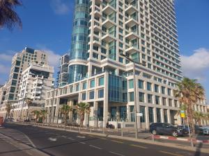 a tall building with palm trees in front of a street at Aparthotel Banana Beach in Tel Aviv