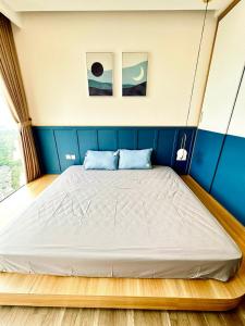 een groot bed in een kamer met een blauwe muur bij Fami Homestay - Ecopark Hưng Yên in HÆ°ng YÃªn