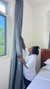 una mujer parada junto a una ventana en un dormitorio en PM Lodge and Restaurant en Matemwe