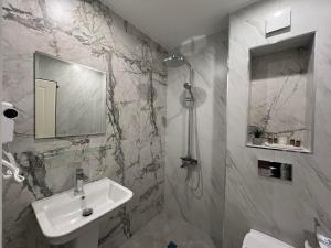 a white bathroom with a sink and a shower at Хотел VIP APART HOUSE in Pleven