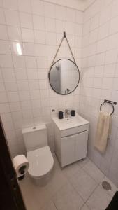 a white bathroom with a toilet and a mirror at Refugio dos Lima in Ericeira