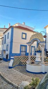 a blue and white house with a fountain in front of it at Refugio dos Lima in Ericeira