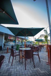 a patio with tables and chairs and a green umbrella at Hotel Fun City (Best Review Hotel In Navsari) in Navsāri