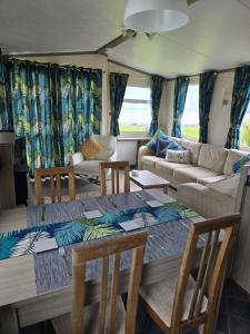 a living room with a table and chairs and a couch at Bayview at Pengarreg in Llanrhystyd