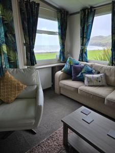 a living room with a couch and a table and a window at Bayview at Pengarreg in Llanrhystyd