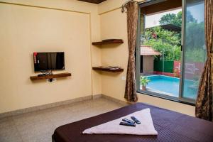um quarto com uma cama, uma televisão e uma piscina em Seasons The Resort em Alibag