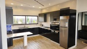eine Küche mit schwarzen Schränken und einem Kühlschrank aus Edelstahl in der Unterkunft ROSE in Umm el ‘Amad