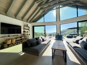 ein Wohnzimmer mit Sofas, Fernseher und Fenstern in der Unterkunft KissHaz in Sovata