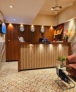 a man sitting at a bar in a room with clocks at Hotel Czar Inn - Vashi Navi Mumbai in Navi Mumbai