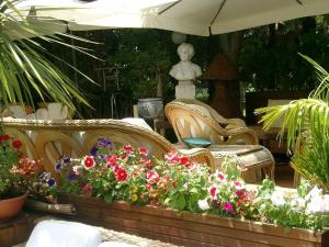 リミニにあるhotel bengasiの籐の椅子2脚と花の庭園