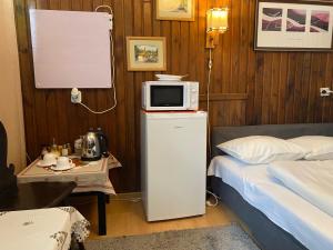 a bedroom with a bed and a microwave on top of a refrigerator at Kwatery Prywatne Hotelik in Barczewo