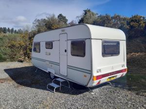a white trailer parked in a gravel lot at The Lakeside Cabin in Longmorn