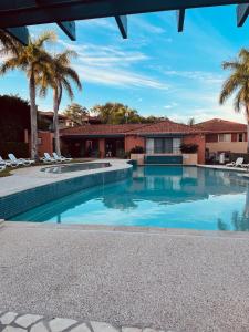 une piscine bordée de palmiers et une maison dans l'établissement Cozy Room Next to Bond University, à Gold Coast
