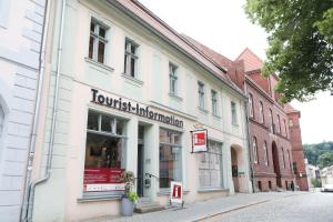 a white building on a street with a store at Kl. Fontane Ferienwohnung Bad Freienwalde direkt am Markt in Bad Freienwalde