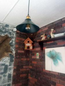 una luz colgando de una pared de ladrillo con una casa de pájaros en Вілла Woodman, en Skhidnytsya