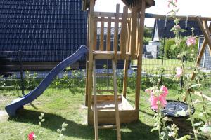 a wooden playground with a slide in a yard at Us nige Wark - Familienfreundliches Haus an der Nordsee in Spieka-Neufeld