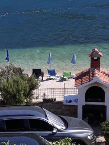 a car parked next to a beach with chairs and umbrellas at Apartments Bulovic Bozo Ap1 in Podglavica