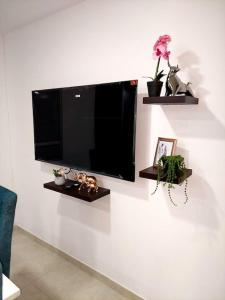 Elle comprend une télévision à écran plat suspendue sur un mur blanc. dans l'établissement Apartamento en condominio con piscina, à Villavicencio