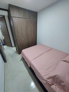 - une chambre avec un lit rose et une armoire en bois dans l'établissement Apartamento en condominio con piscina, à Villavicencio