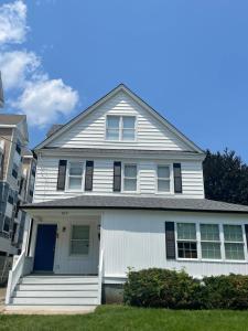 a white house with black shutters on it at Room near the beach in long branch in Long Branch