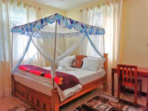 a bedroom with a canopy bed and a table at Sinthia Hotel Apartments in Chaki Chaki