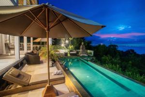 a swimming pool with an umbrella next to a house at The Puncak Private Villa in Nusa Lembongan
