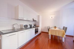 a kitchen with white cabinets and a wooden floor at Sunlight in Lugano