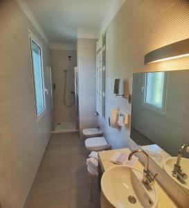 uma casa de banho com 2 WC, um lavatório e um chuveiro em Hotel Valdor em Cavallino-Treporti