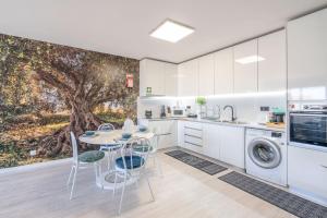 a kitchen with a table and chairs and a tree mural at RA FIGUEIRA DA FOZ in Figueira da Foz