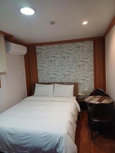 a bedroom with a white bed and a brick wall at Gooreumseong motel in Seoul
