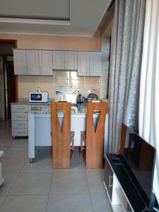 une cuisine avec un comptoir avec deux chaises et une table dans l'établissement Kigali Grand Villa, à Kigali