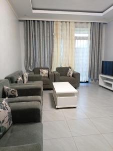 - un salon avec des canapés et une télévision dans l'établissement Kigali Grand Villa, à Kigali