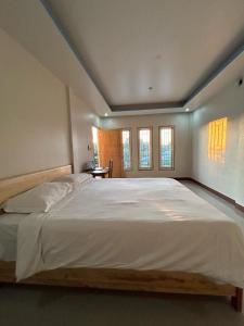 a bedroom with a large white bed with windows at FOUR-G HOMESTAY & Komodo Tour in Labuan Bajo