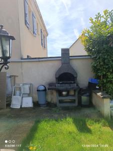 an outdoor grill in a yard next to a building at Maison romantique entre deux fleuves chez l'habitant in Montereau-Fault-Yonne