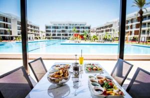 a table with food on it with a view of a pool at Courtyard Long Beach Holiday Resort in Iskele