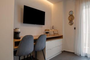 a kitchen with two chairs and a desk with a television on the wall at Thessalonian Suite I - 2 Steps from White Tower in Thessaloniki