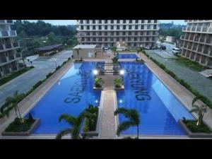 a large swimming pool with palm trees and a large building at D' Kikays Saekyung Village 1 in Basbas