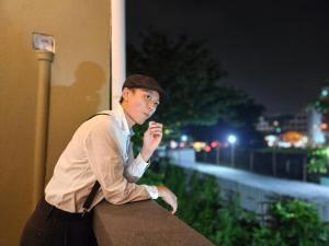 a woman is sitting on a wall at night at 85 Boutique Hotel in Ipoh