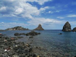 a group of rocks in the water near the beach at Terrazza Faraglioni in Acitrezza