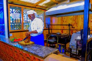 Um homem de pé numa cozinha a preparar comida. em Malibu Lounge Bar & Restaurant em Kisii