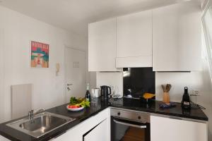 een witte keuken met een wastafel en een aanrecht bij Santi Apartment Few Min From Lake - Happy Rentals in Lugano