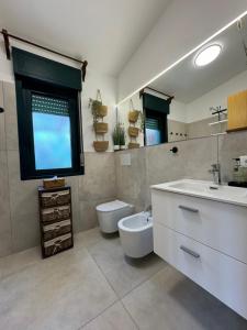 bagno con lavandino, servizi igienici e finestra di Villa vista Marianello a Licata