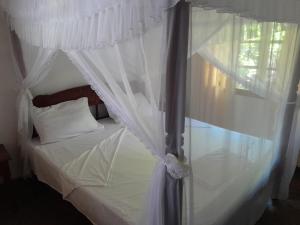 a bedroom with a white canopy bed with a window at Lion Garden Villa 7 in Malindi