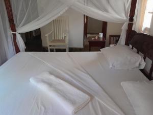 een wit bed met twee witte handdoeken erop bij Lion Garden Villa 7 in Malindi