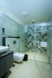 uma casa de banho com um WC e uma cabina de duche em vidro. em AJ GRAND ELITE HOTEL em Mangalore